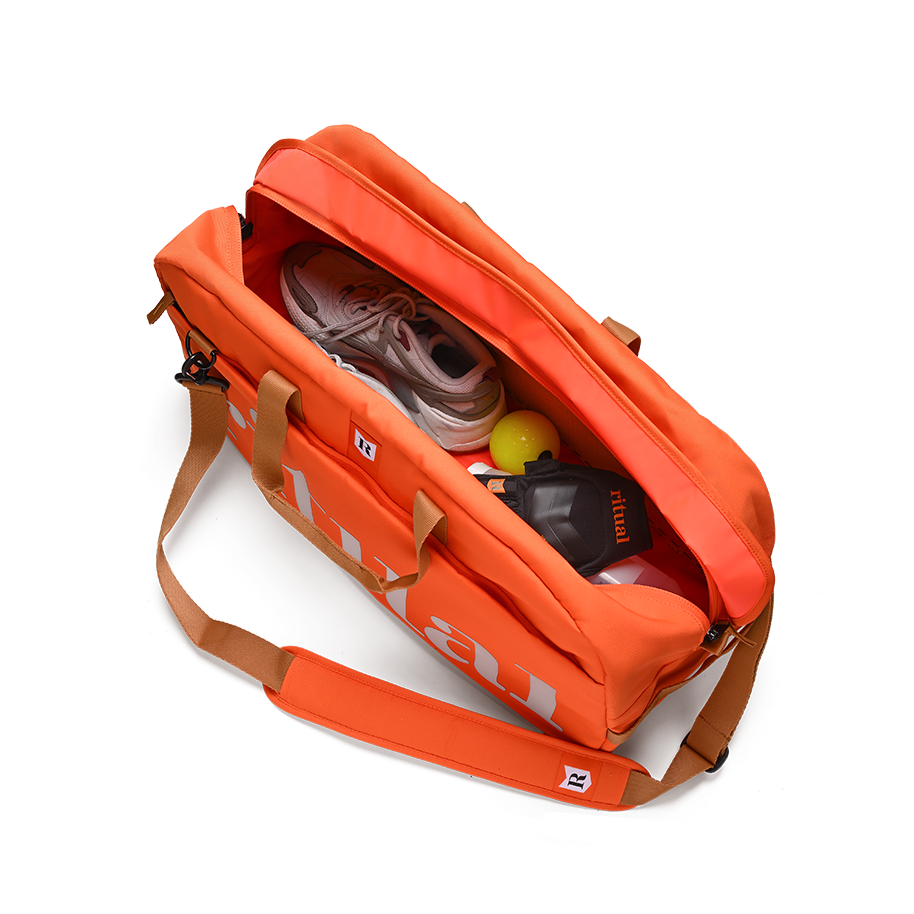 Ritual Calibre hockey duffle bag orange with brown straps containing sports equipment