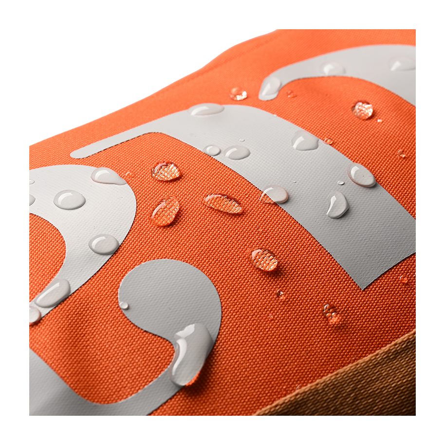 Ritual Hockey orange tactic stick bag, Close-up of an orange fabric surface with water droplets and gray shapes